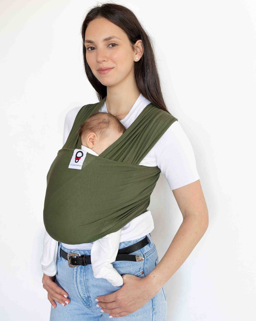 אישה גבוהה נושאת את התינוק שלה במנשא בד בצבע ירוק מבד מודל דק ונושם מגיל לידה
