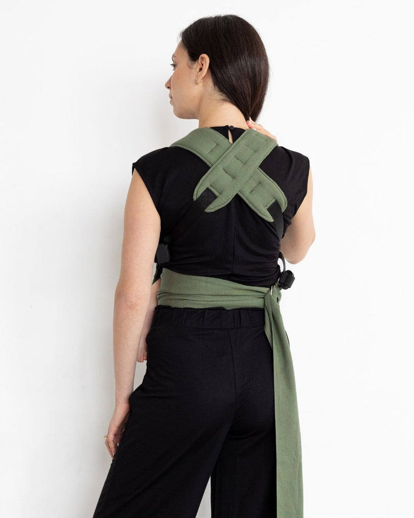 דוגמנית לבושה בבגדים שחורים נושאת תינוק במנח בטן לבטן עם מנשא תינוק בצבע ירוק מבד פשתן של חברת אורבן בייבי ראפ