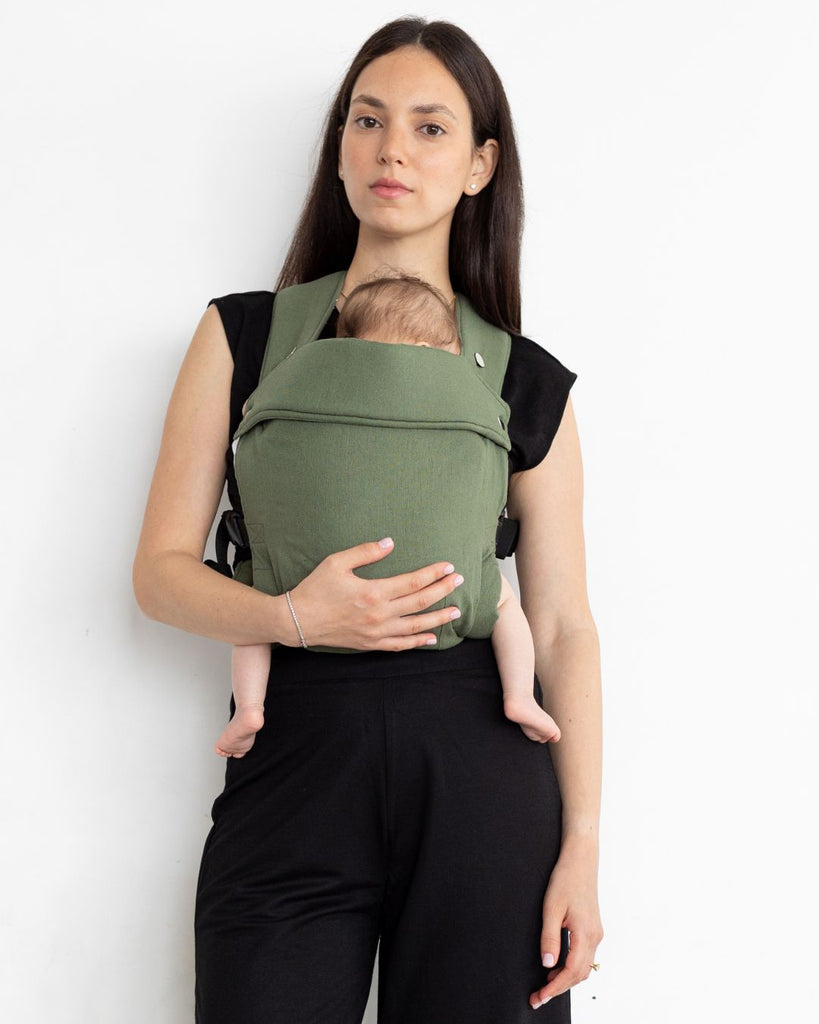 דוגמנית לבושה בבגדים שחורים נושאת תינוק במנח בטן לבטן עם מנשא תינוק בצבע ירוק מבד פשתן של חברת אורבן בייבי ראפ