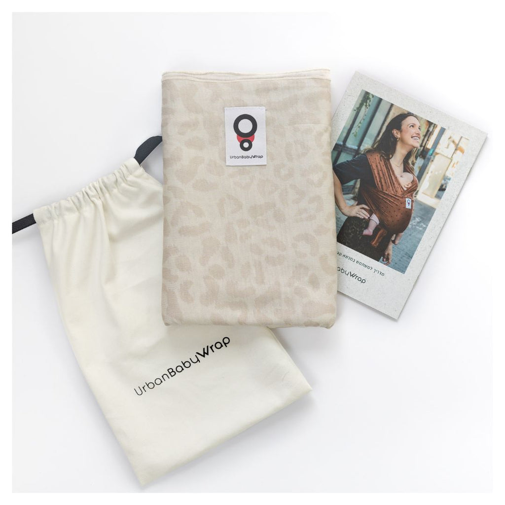 תמונת פק שוט של מנשא בד מגיל לידה של חברת אורבן בייבי מבד מודל בדוגמא מנומרת בצבעים בהירים של אופוויט ובז' ארוז כמתנת לידה עם שקית אחסון המדריך למשתמש 