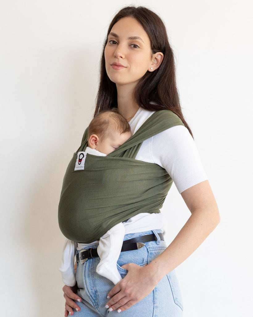 אישה גבוהה נושאת את התינוק שלה במנשא בד בצבע ירוק מבד מודל דק ונושם מגיל לידה