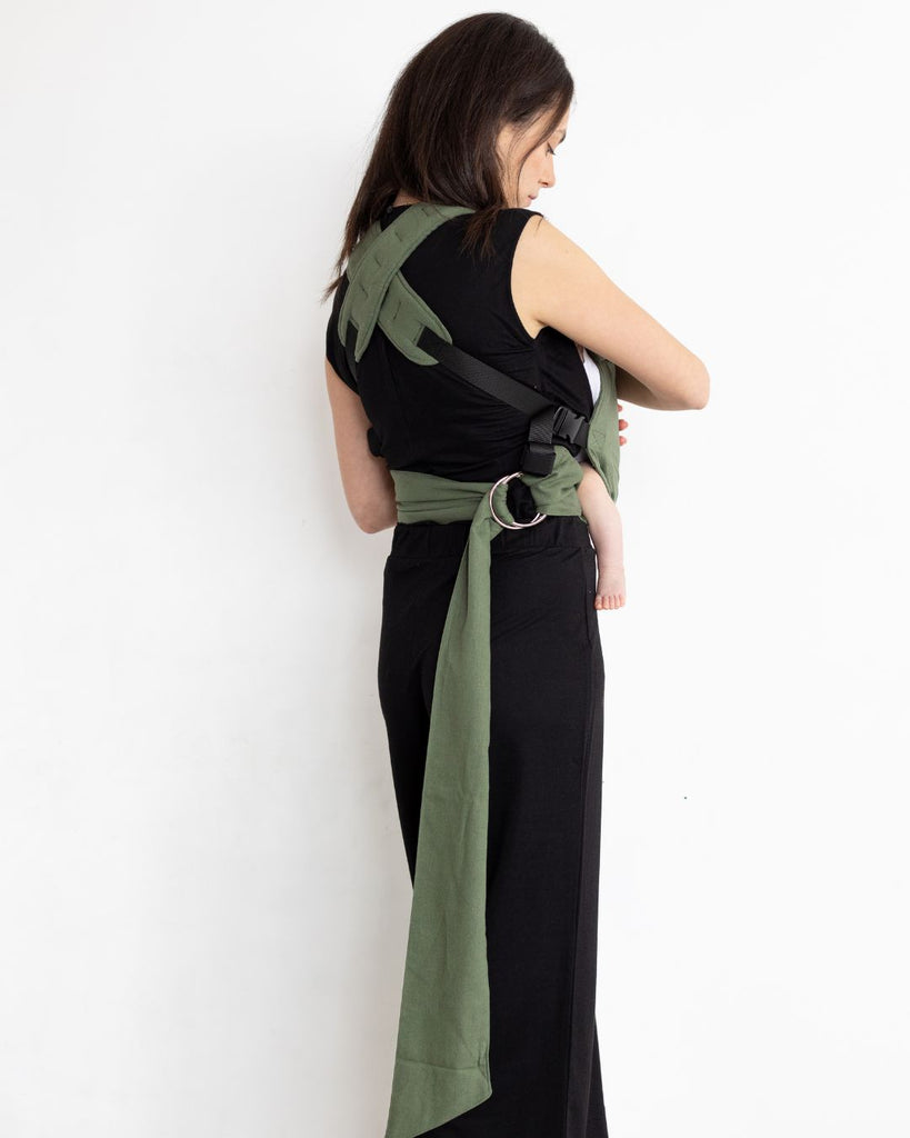 דוגמנית לבושה בבגדים שחורים נושאת תינוק במנח בטן לבטן עם מנשא תינוק בצבע ירוק מבד פשתן של חברת אורבן בייבי ראפ