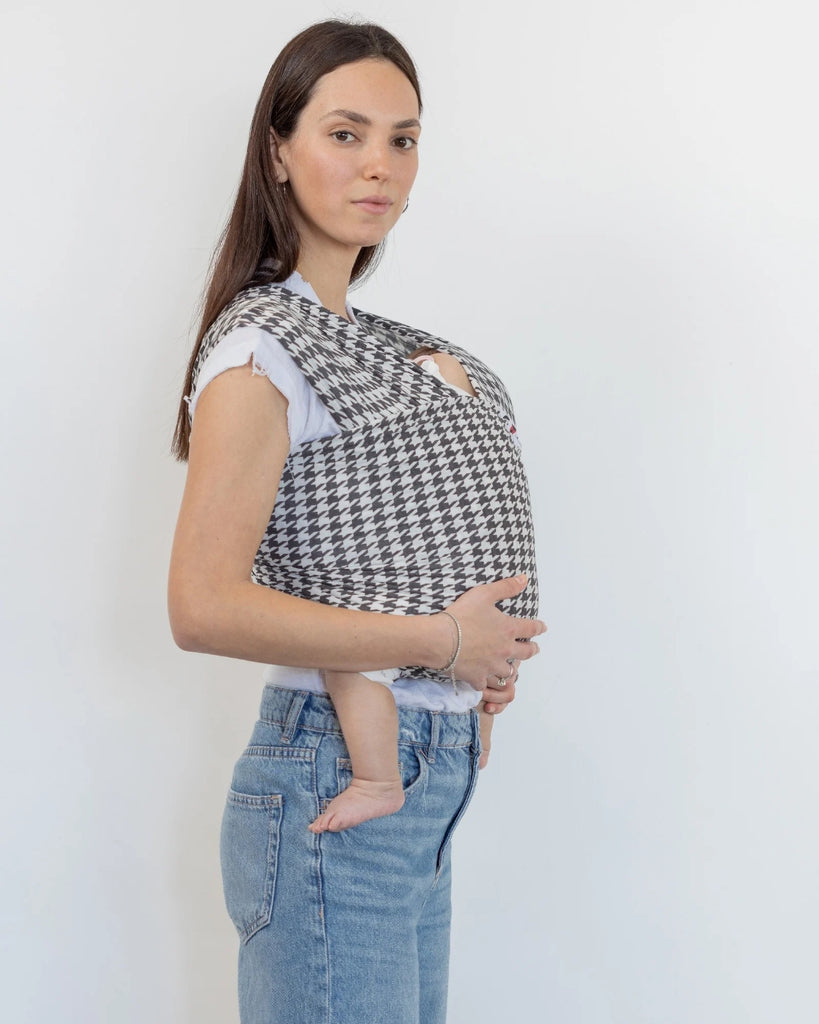 דוגמנית עם תינוק בן ארבע חודשים ישן בתוך מנשא קשירה מגיל לידה מבד מודל ללא לייקרה בדוגמת פפיטה בצבעים של אפור כהה וקרם של חברת אורבן בייבי ראפ