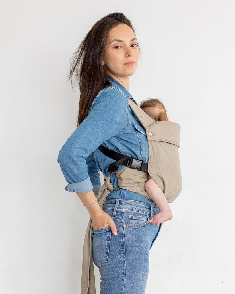 דוגמנית בתמונת פרופיל נושאת תינוקת בת 5 חודשים במנשא ילקוט מגיל לידה בצבע בז' מבד פשתן טבעי של חברת אורבן בייבי ראפ במנח בטן לבטן  