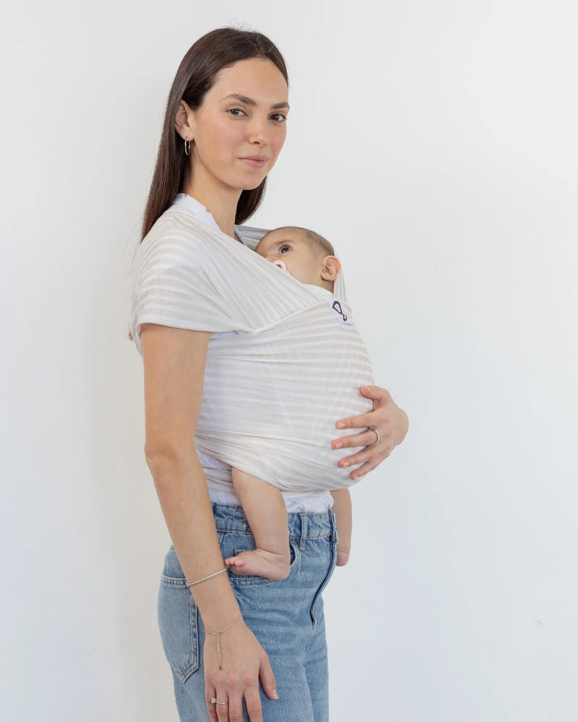 דוגמנית עם תינוק בן ארבע חודשים ישן בתוך מנשא קשירה מגיל לידה מבד מודל ללא לייקרה בדוגמת פסים לבן ובז' של חברת אורבן בייבי ראפ 