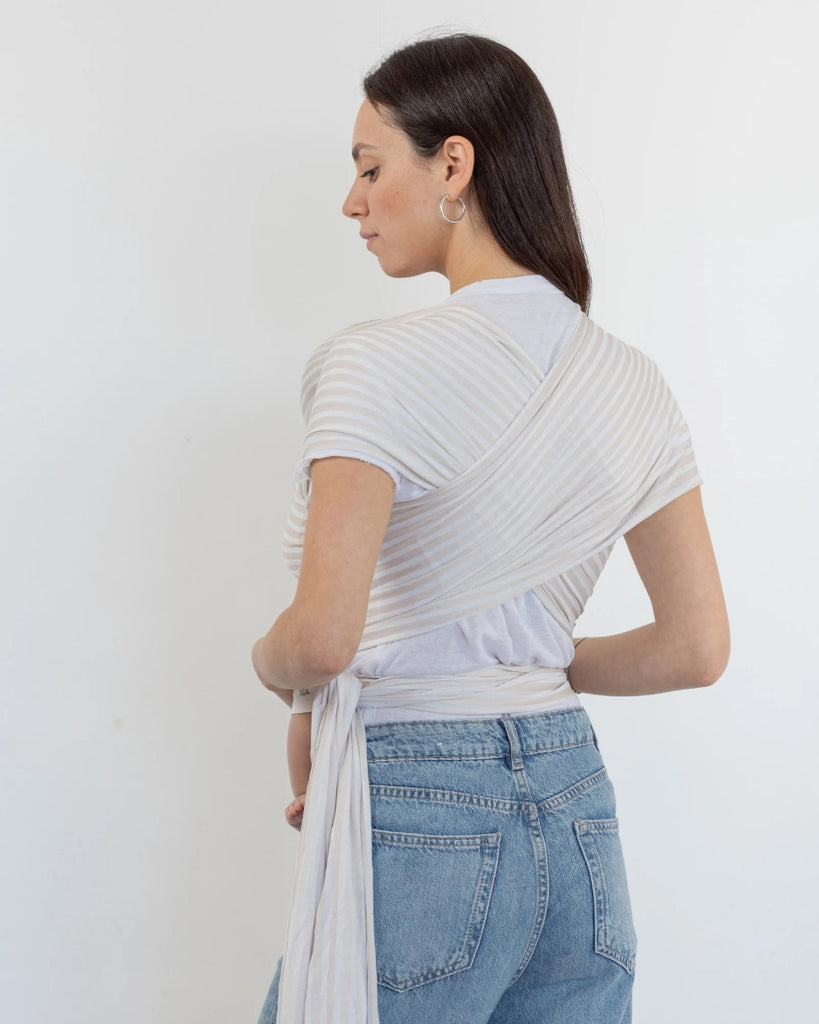 דוגמנית עם תינוק בן ארבע חודשים ישן בתוך מנשא קשירה מגיל לידה מבד מודל ללא לייקרה בדוגמת פסים לבן ובז' של חברת אורבן בייבי ראפ 