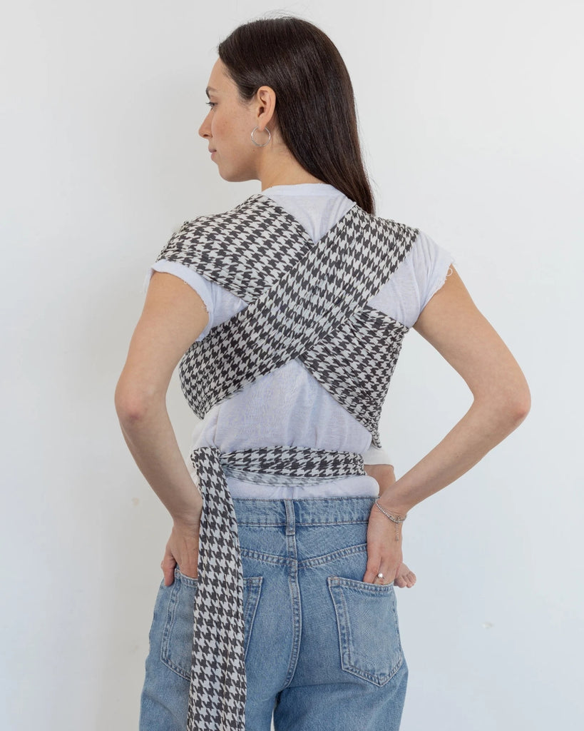 דוגמנית עם תינוק בן ארבע חודשים ישן בתוך מנשא קשירה מגיל לידה מבד מודל ללא לייקרה בדוגמת פפיטה בצבעים של אפור כהה וקרם של חברת אורבן בייבי ראפ